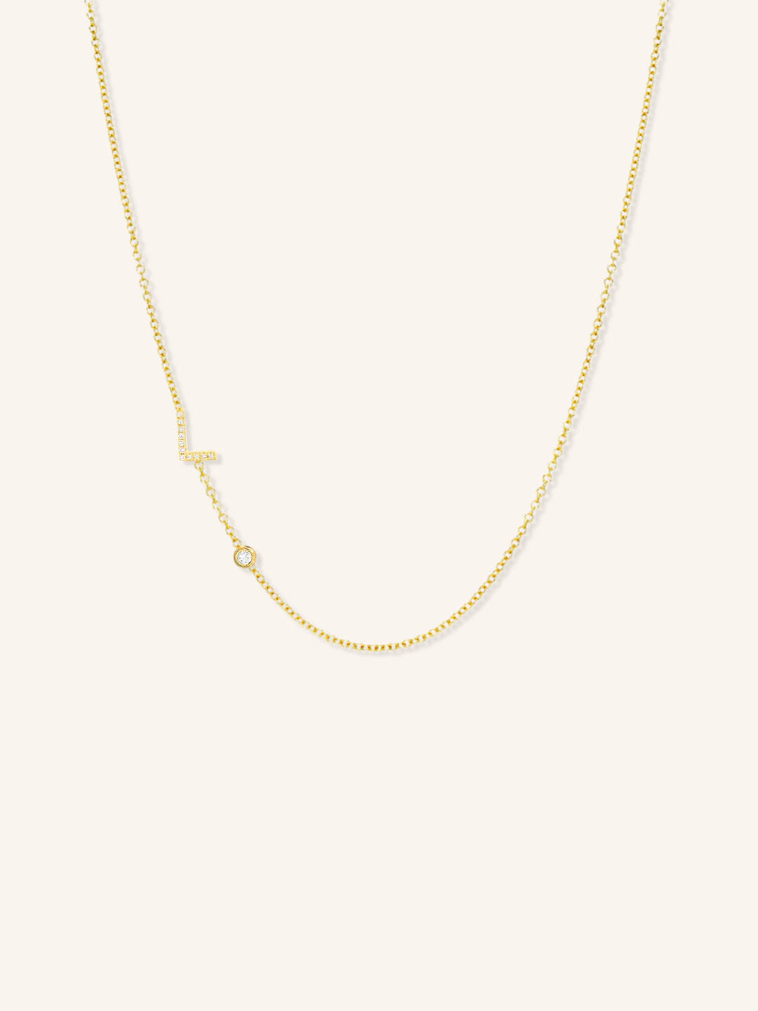 Yellow gold asymmetrical diamond initial L and bezel necklace on white background