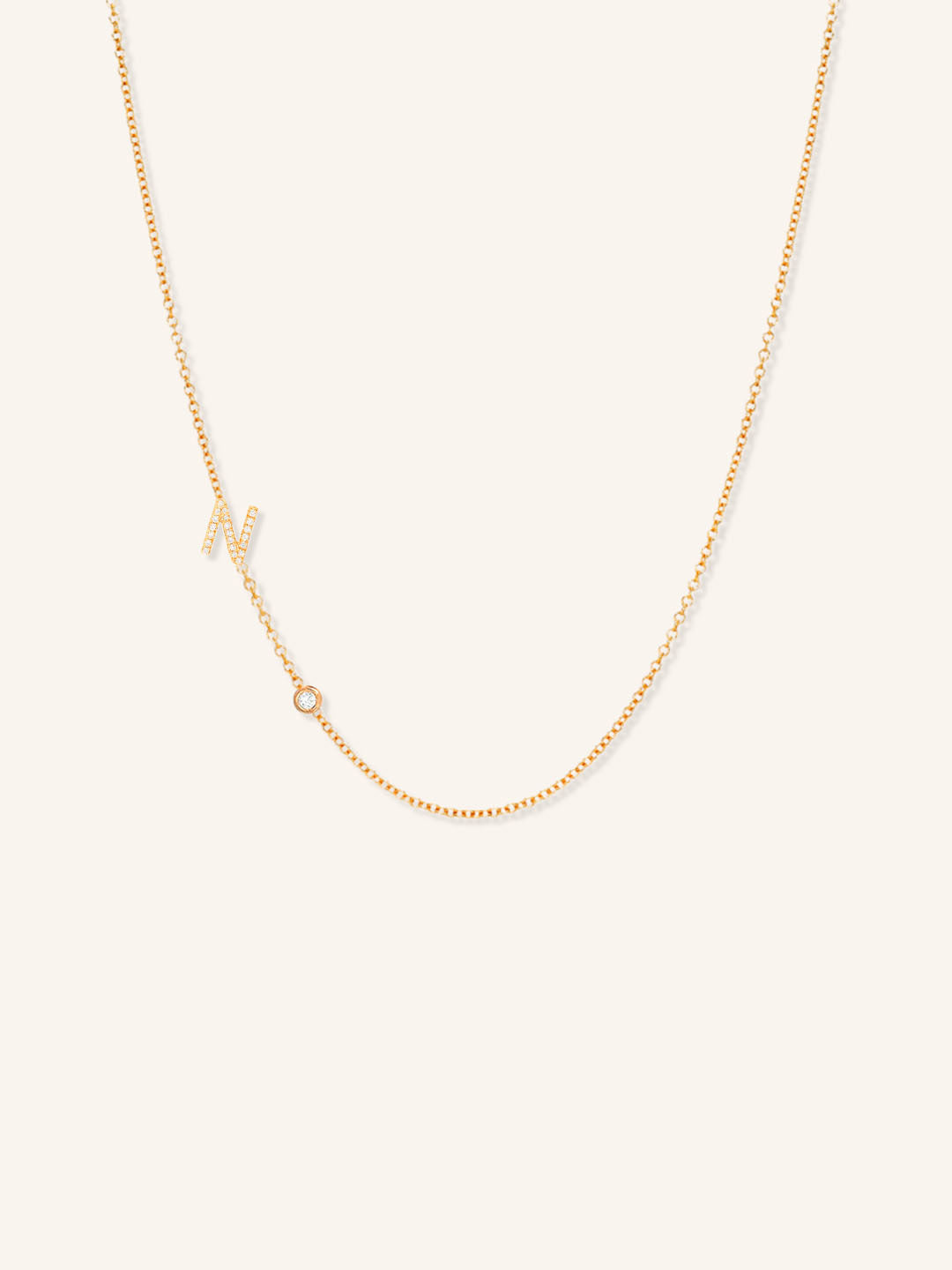 Rose gold asymmetrical diamond initial N and bezel necklace on white background