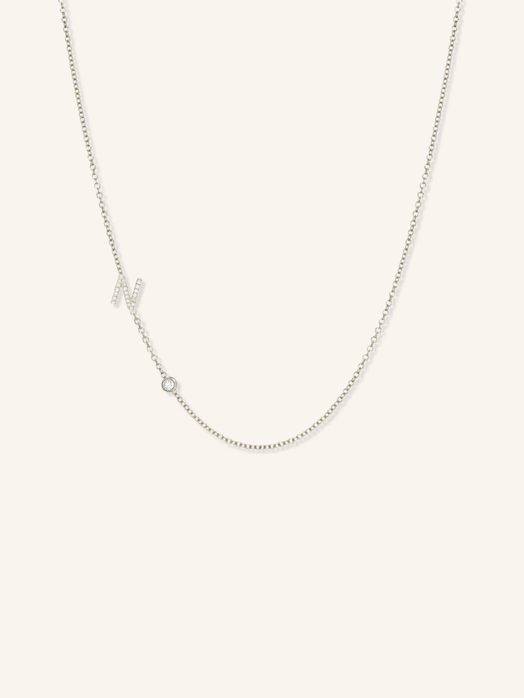 White gold asymmetrical diamond initial N and bezel necklace on white background