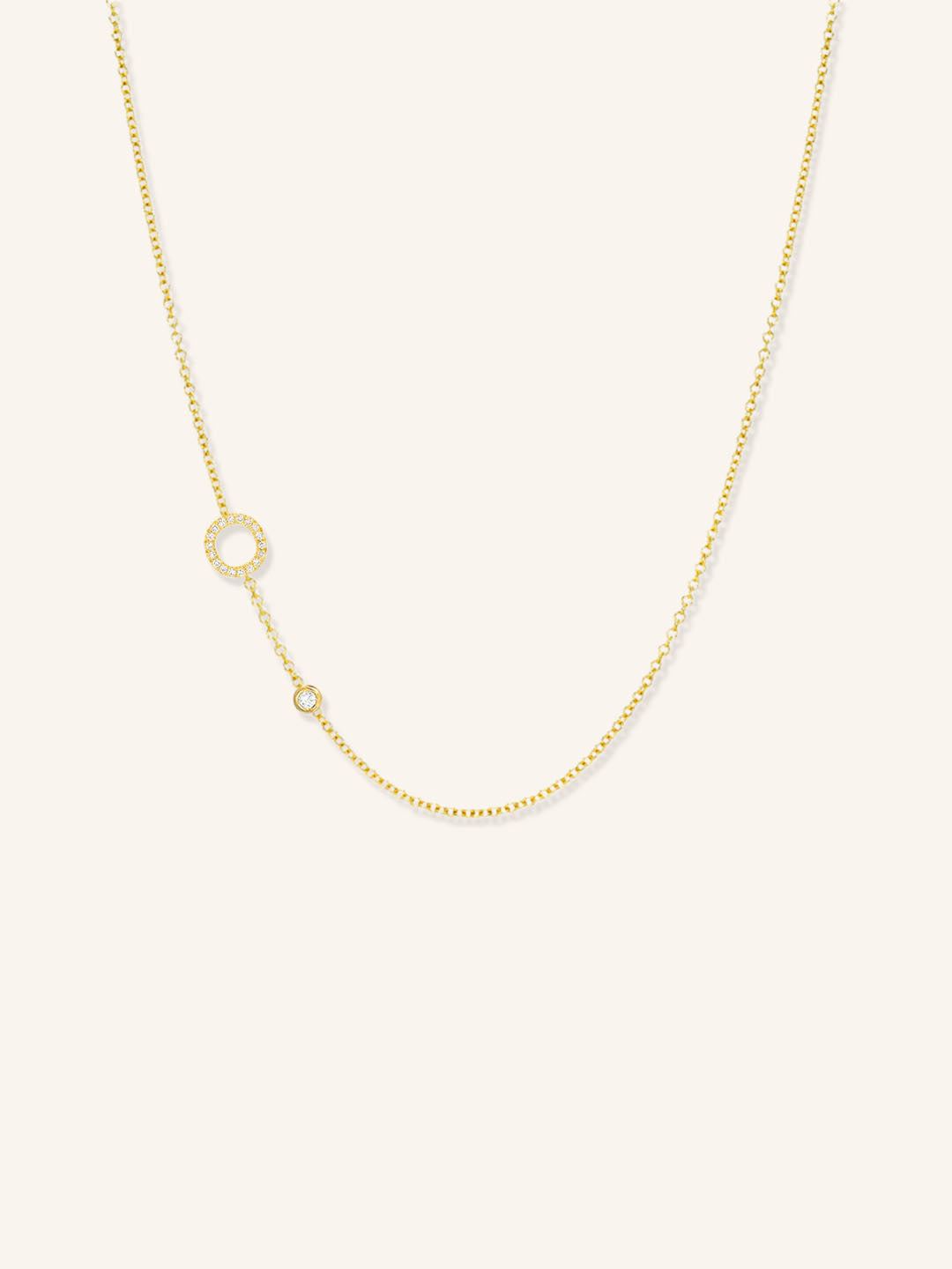 Yellow gold asymmetrical diamond initial O and bezel necklace on white background