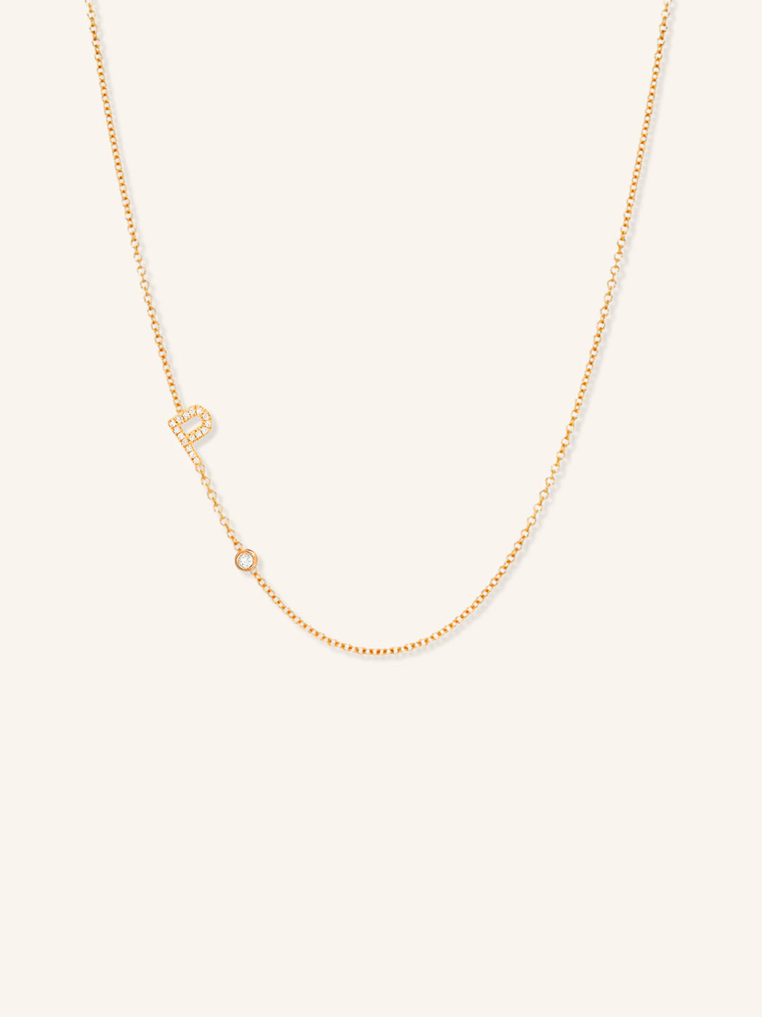 Rose gold asymmetrical diamond initial P and bezel necklace on white background