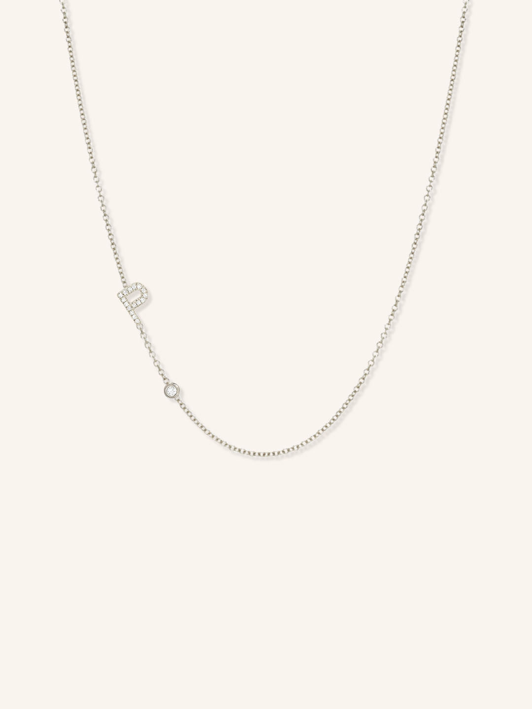 White gold asymmetrical diamond initial P and bezel necklace on white background