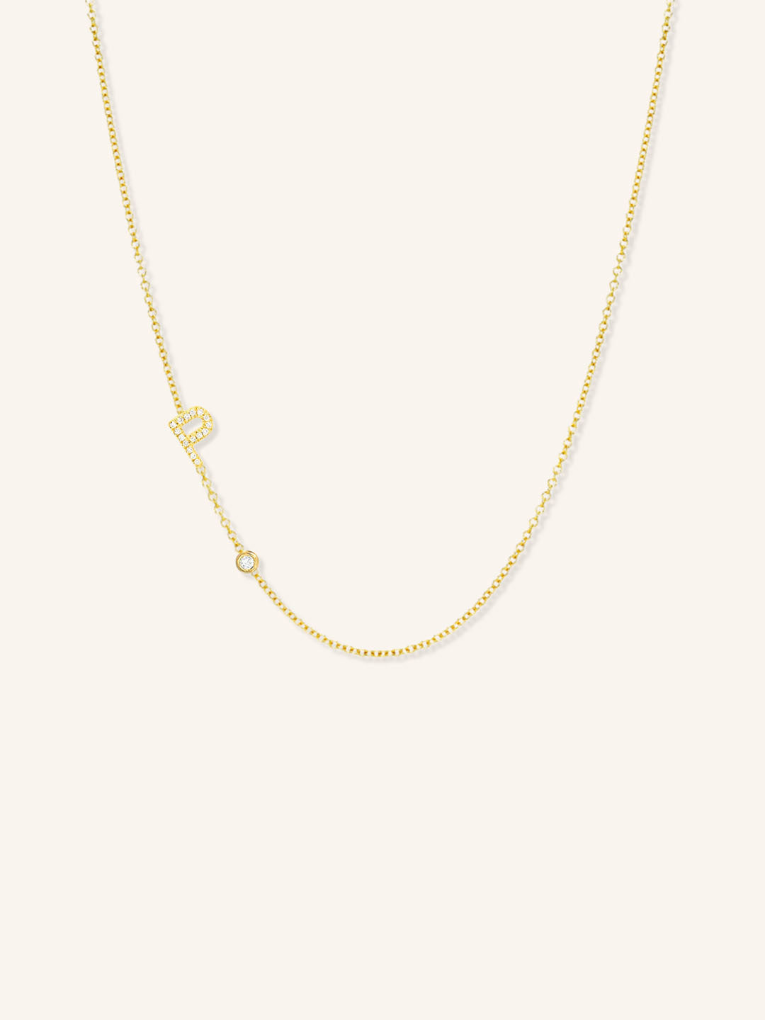 Yellow gold asymmetrical diamond initial P and bezel necklace on white background