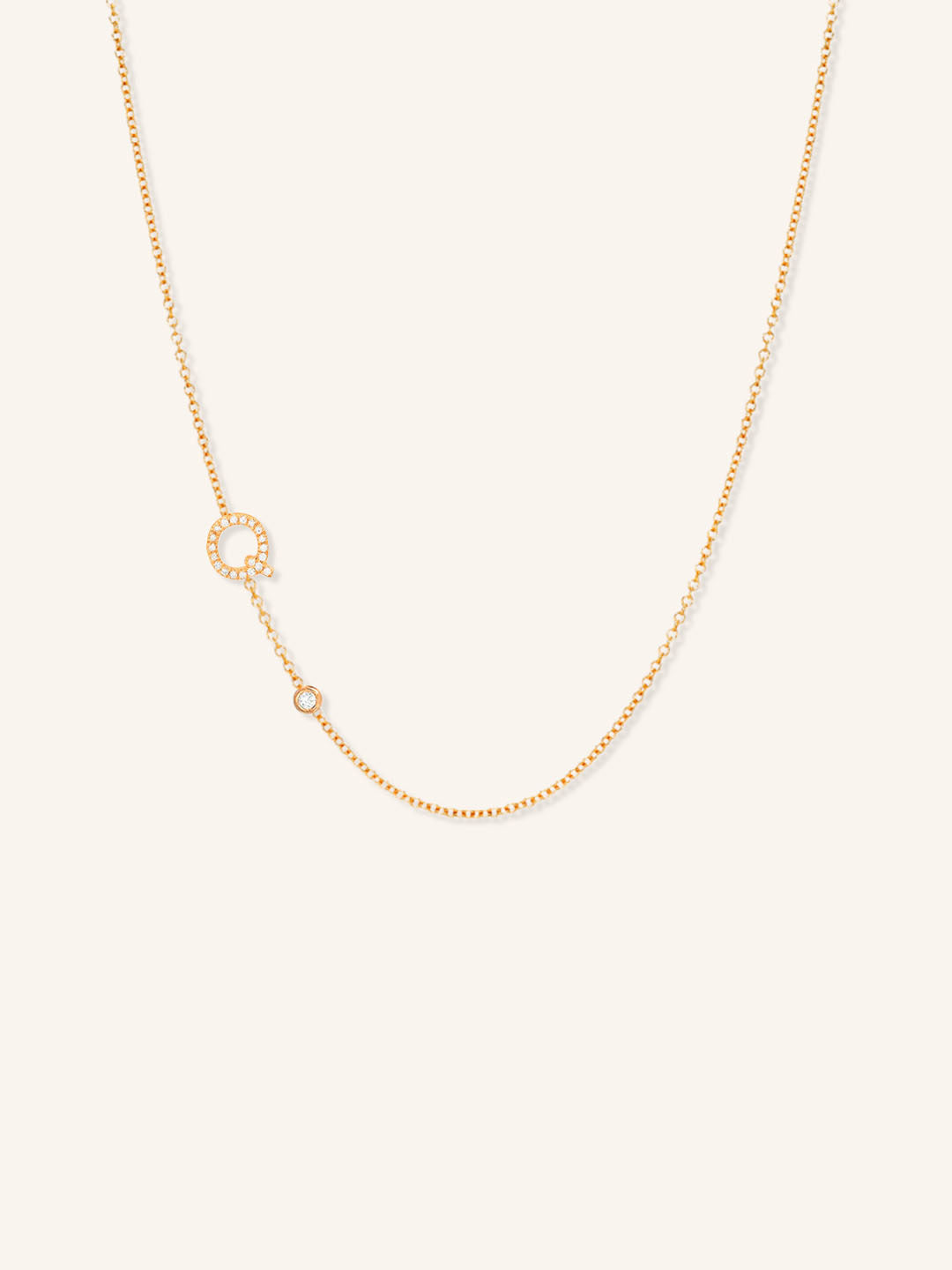 Rose gold asymmetrical diamond initial Q and bezel necklace on white background