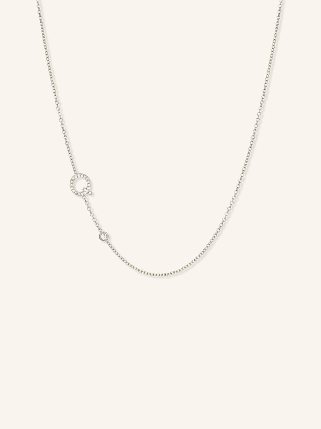 White gold asymmetrical diamond initial Q and bezel necklace on white background