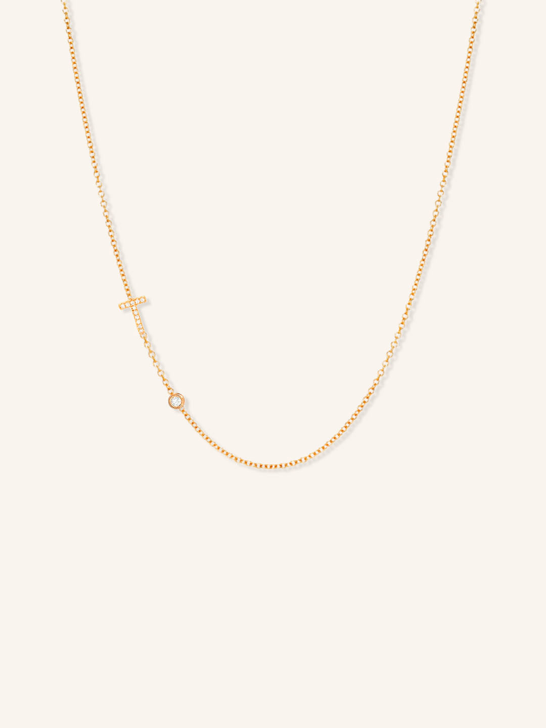 Rose gold asymmetrical diamond initial T and bezel necklace on white background