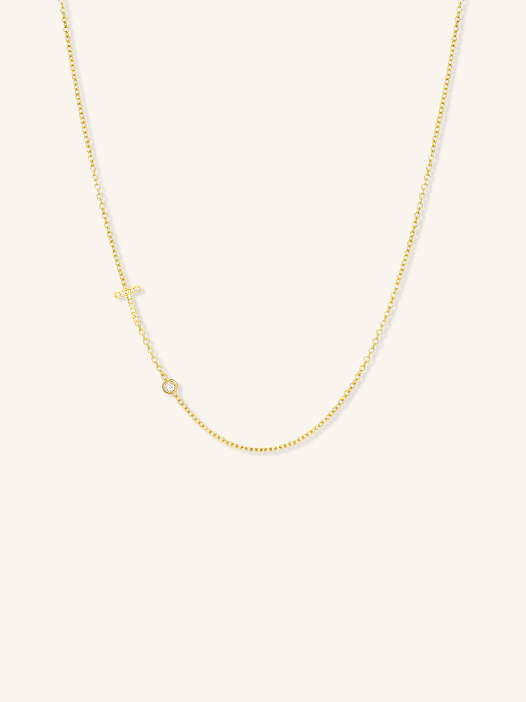 Yellow gold asymmetrical diamond initial T and bezel necklace on white background