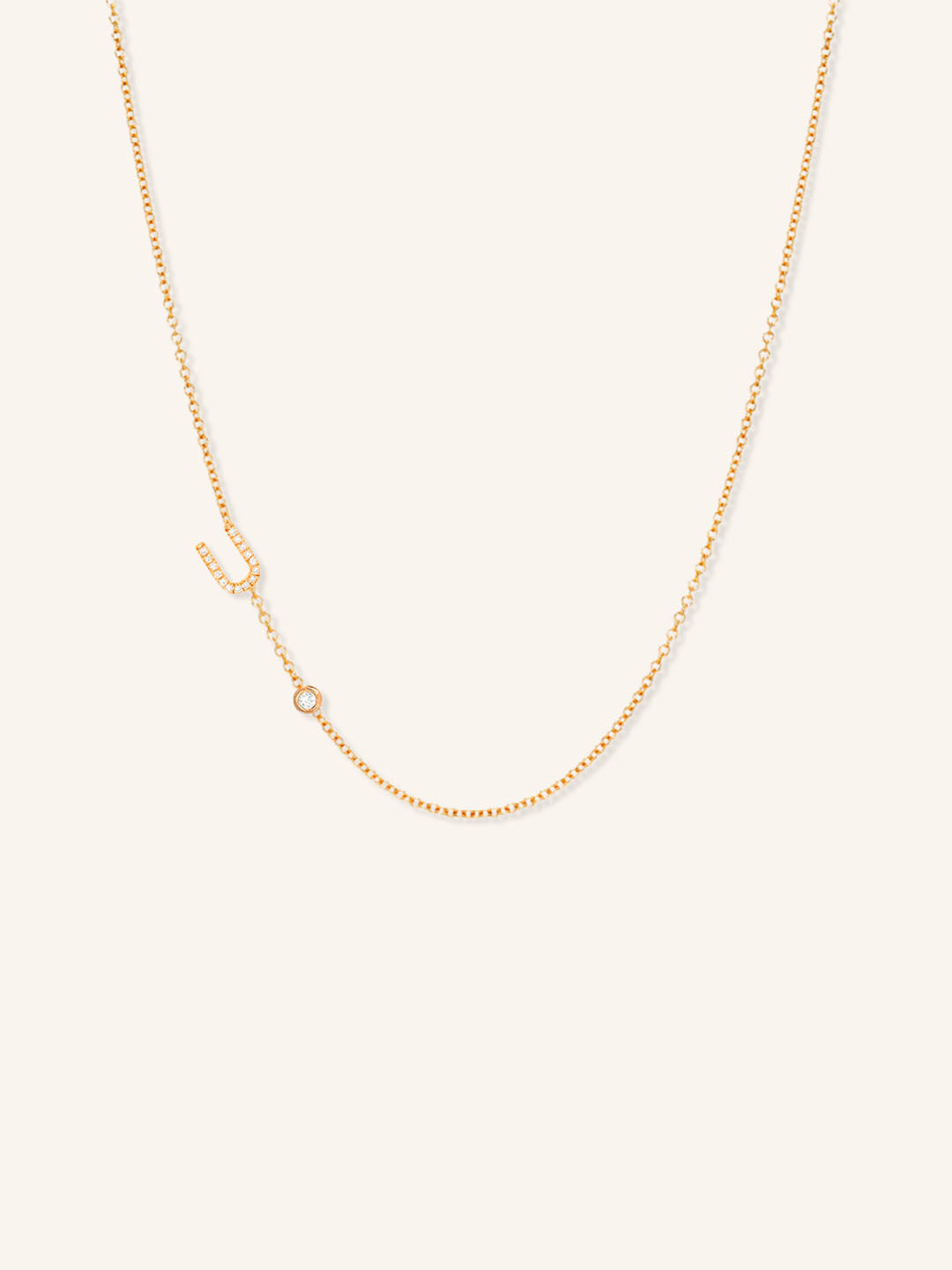 Rose gold asymmetrical diamond initial U and bezel necklace on white background