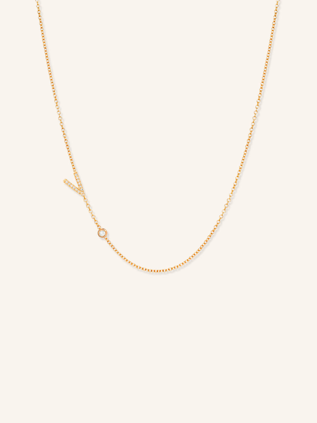 Rose gold asymmetrical diamond initial V and bezel necklace on white background