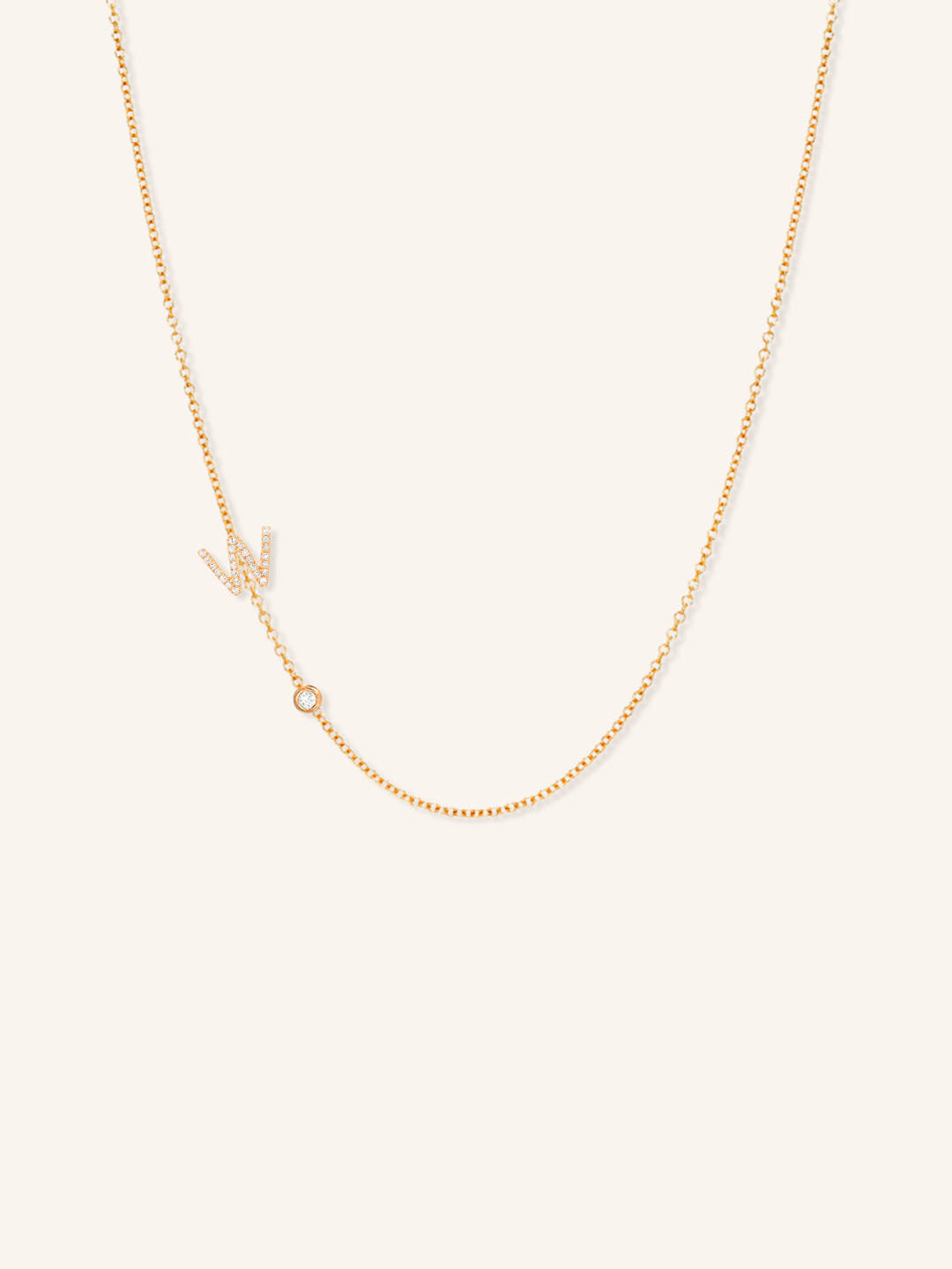 Rose gold asymmetrical diamond initial W and bezel necklace on white background