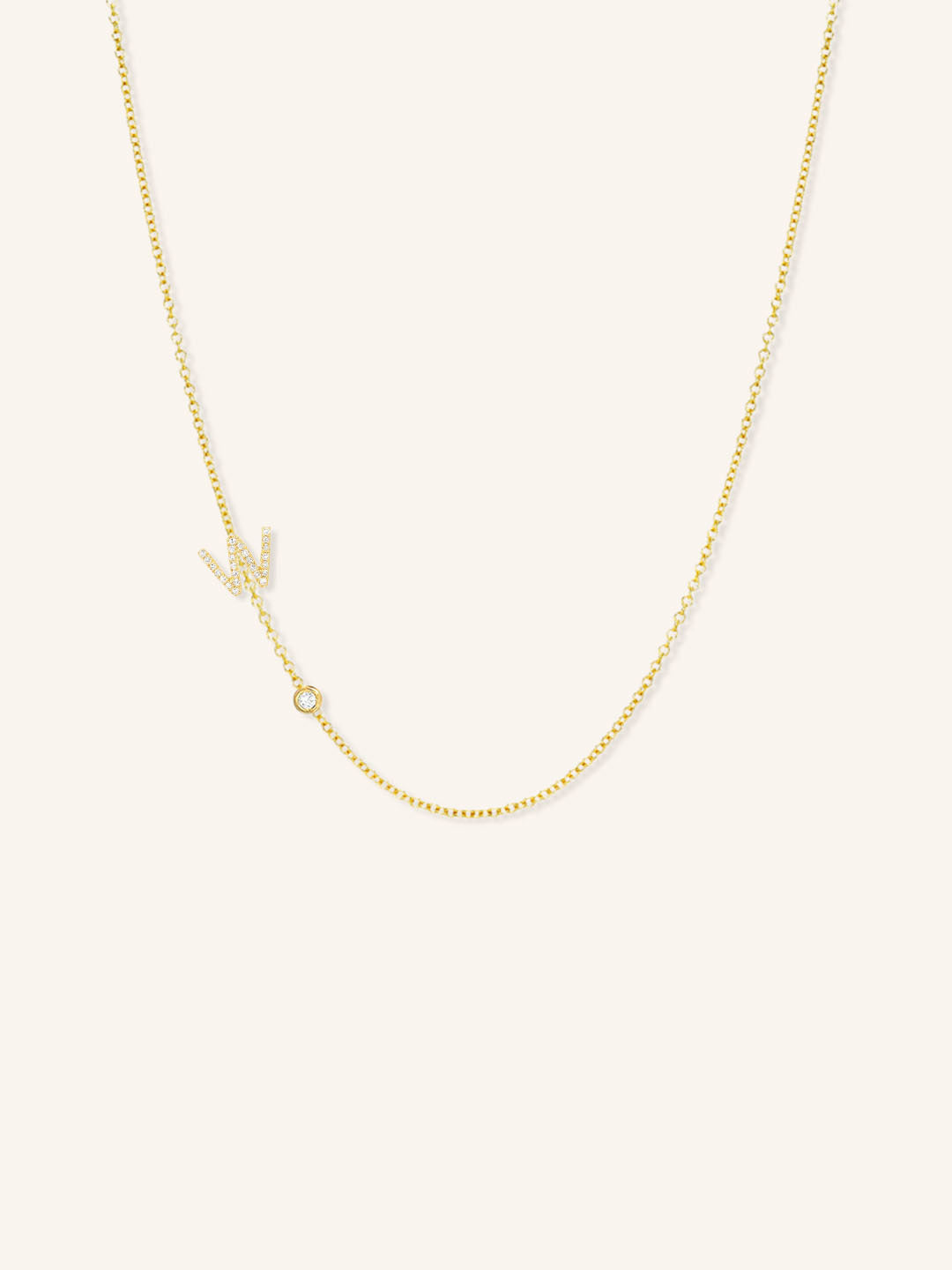 Yellow gold asymmetrical diamond initial W and bezel necklace on white background