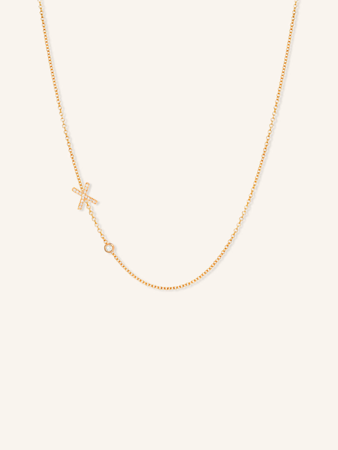 Rose gold asymmetrical diamond initial X and bezel necklace on white background