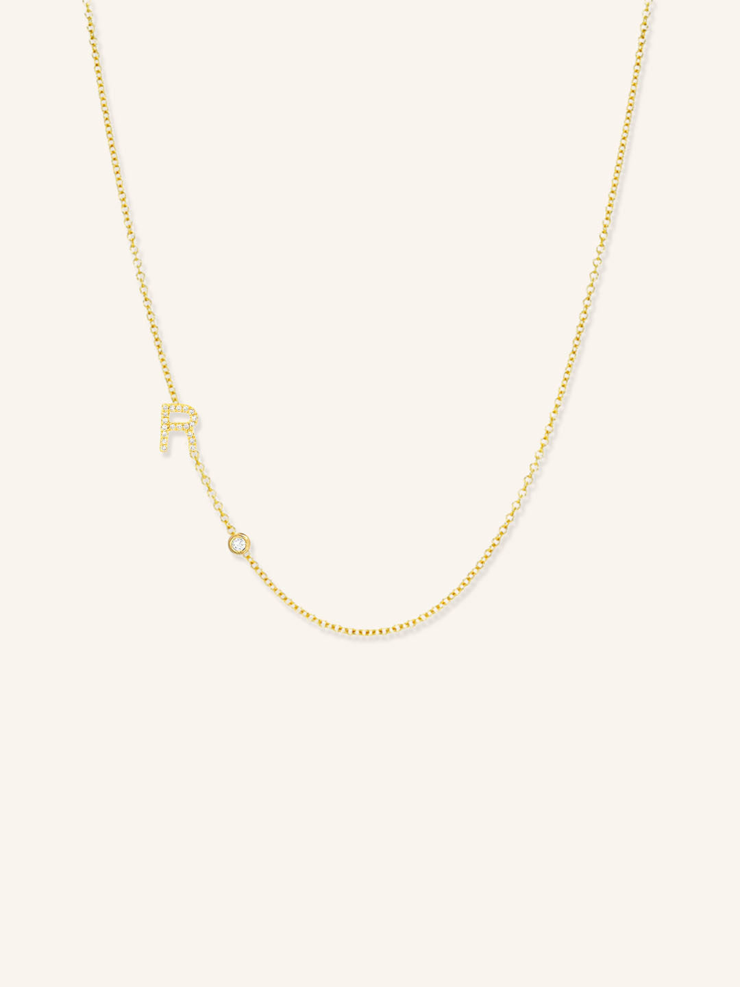 Gold necklace with a small pendant on a light beige background
