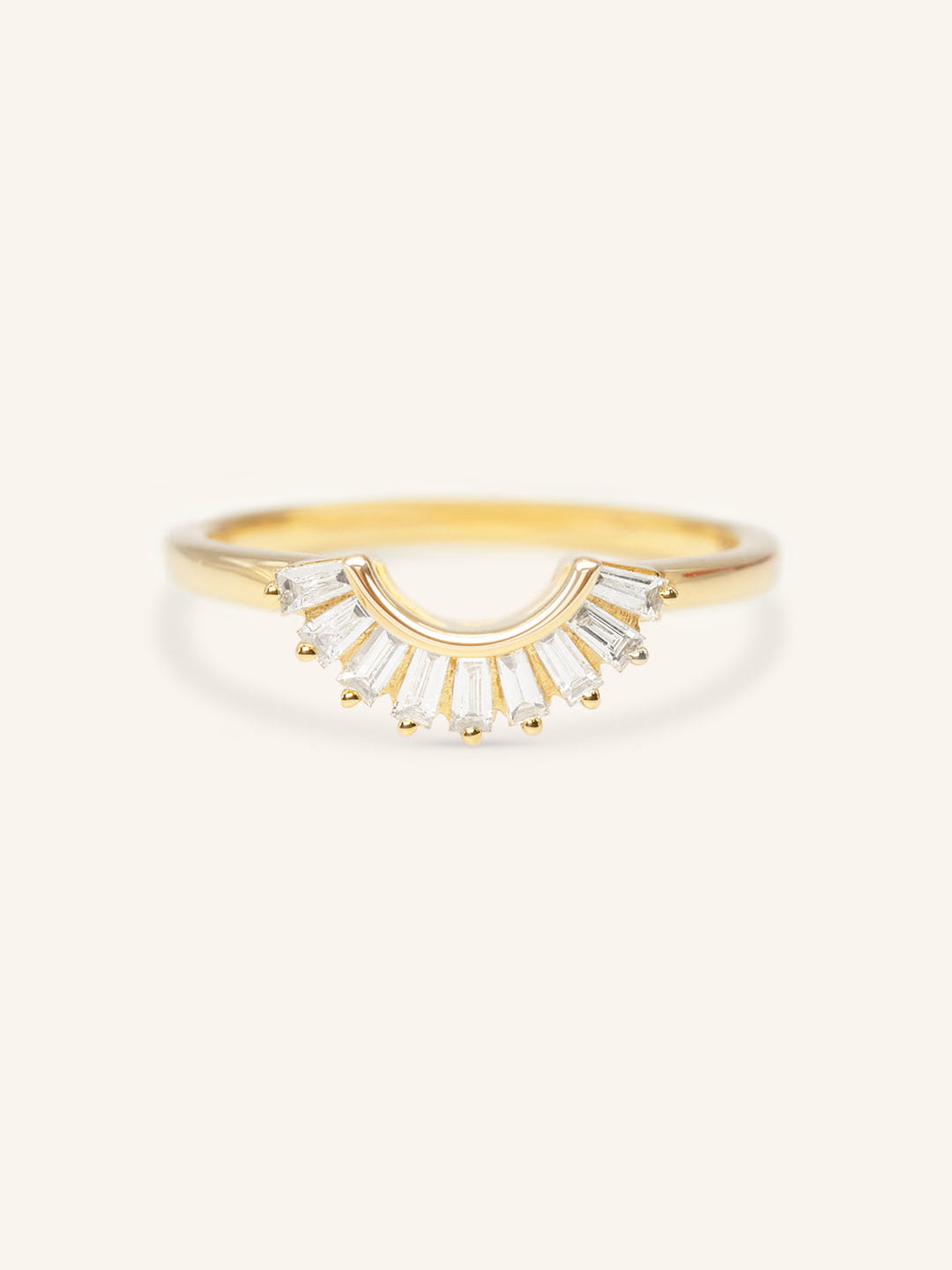 A gold-colored curved wedding band with sparkling tapered baguettes set around its circumference.