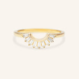 A gold-colored curved wedding band with sparkling tapered baguettes set around its circumference.