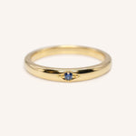 Gold ring with a blue gemstone on a white background