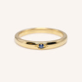 Gold ring with a blue gemstone on a white background