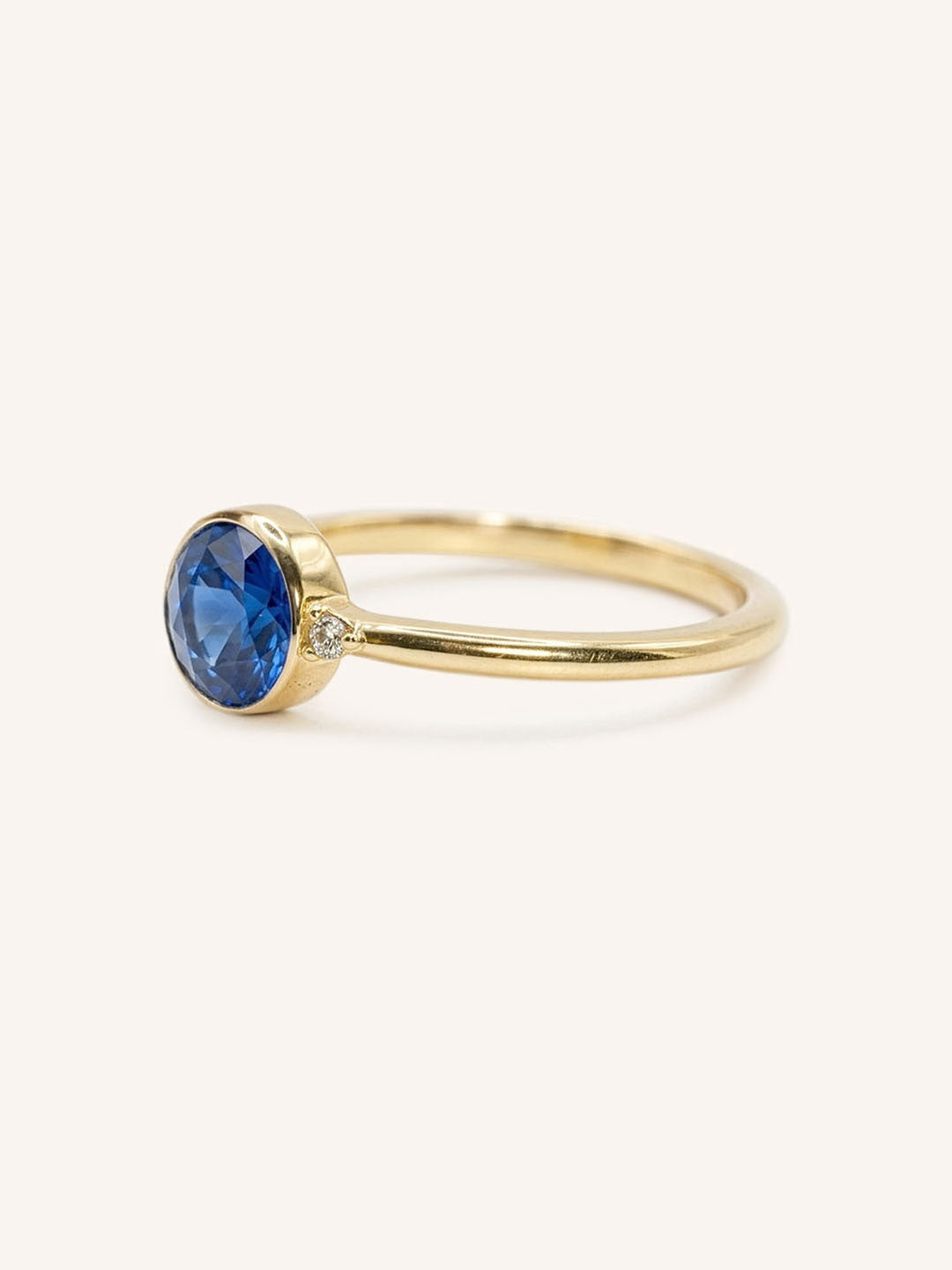 Yellow gold blue sapphire and diamond ring side view on white background
