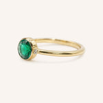 Yellow gold emerald and diamond ring side view on white background