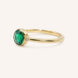 Yellow gold emerald and diamond ring side view on white background