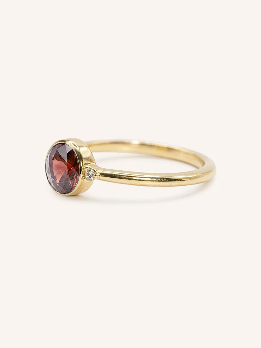 Yellow gold garnet and diamond ring side view on white background