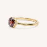 Yellow gold garnet and diamond ring side view on white background
