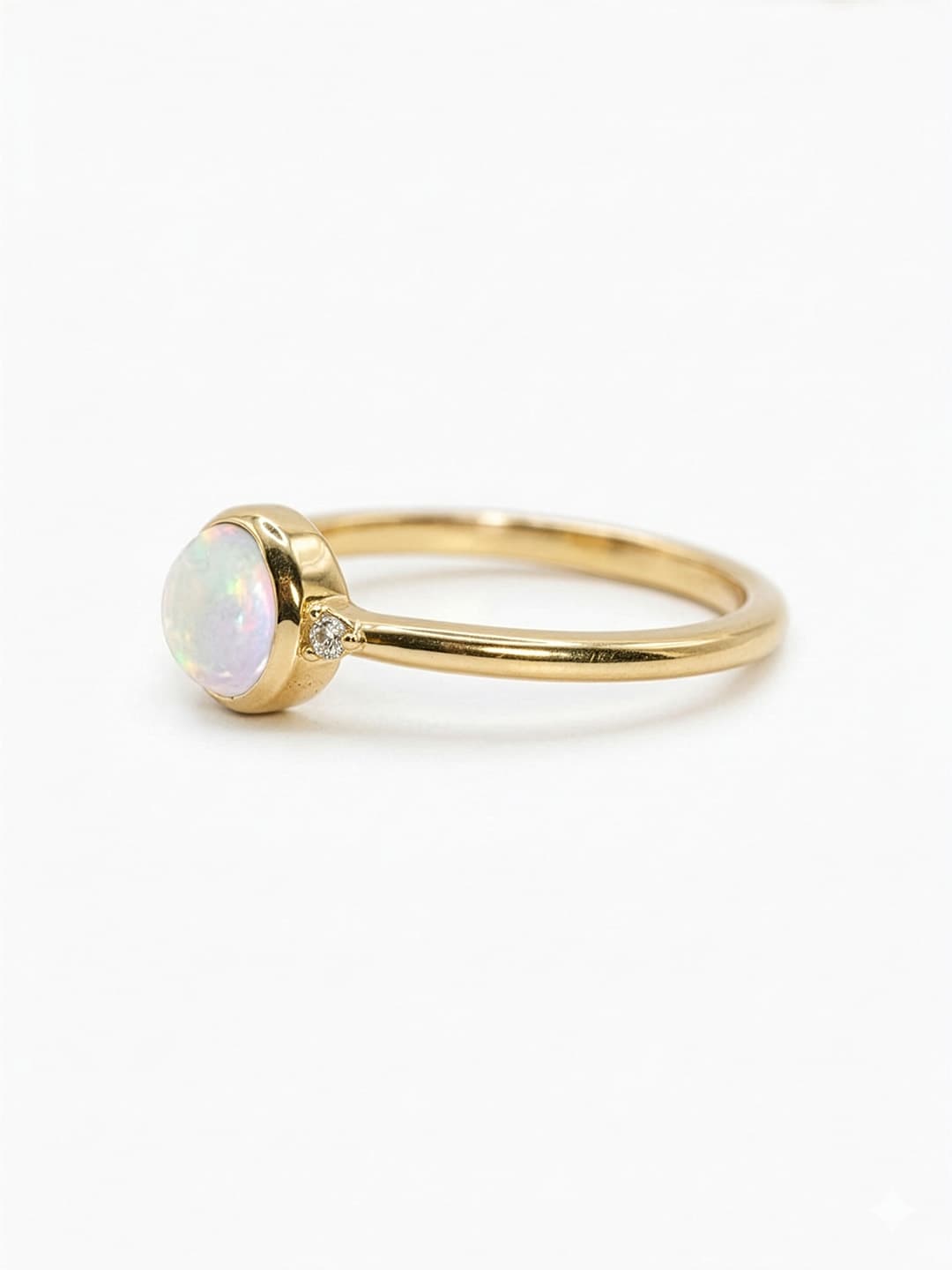 Gold ring with a central opal stone on a white background