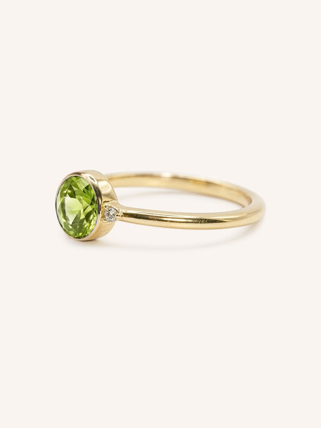Yellow gold peridot and diamond ring side view on white background