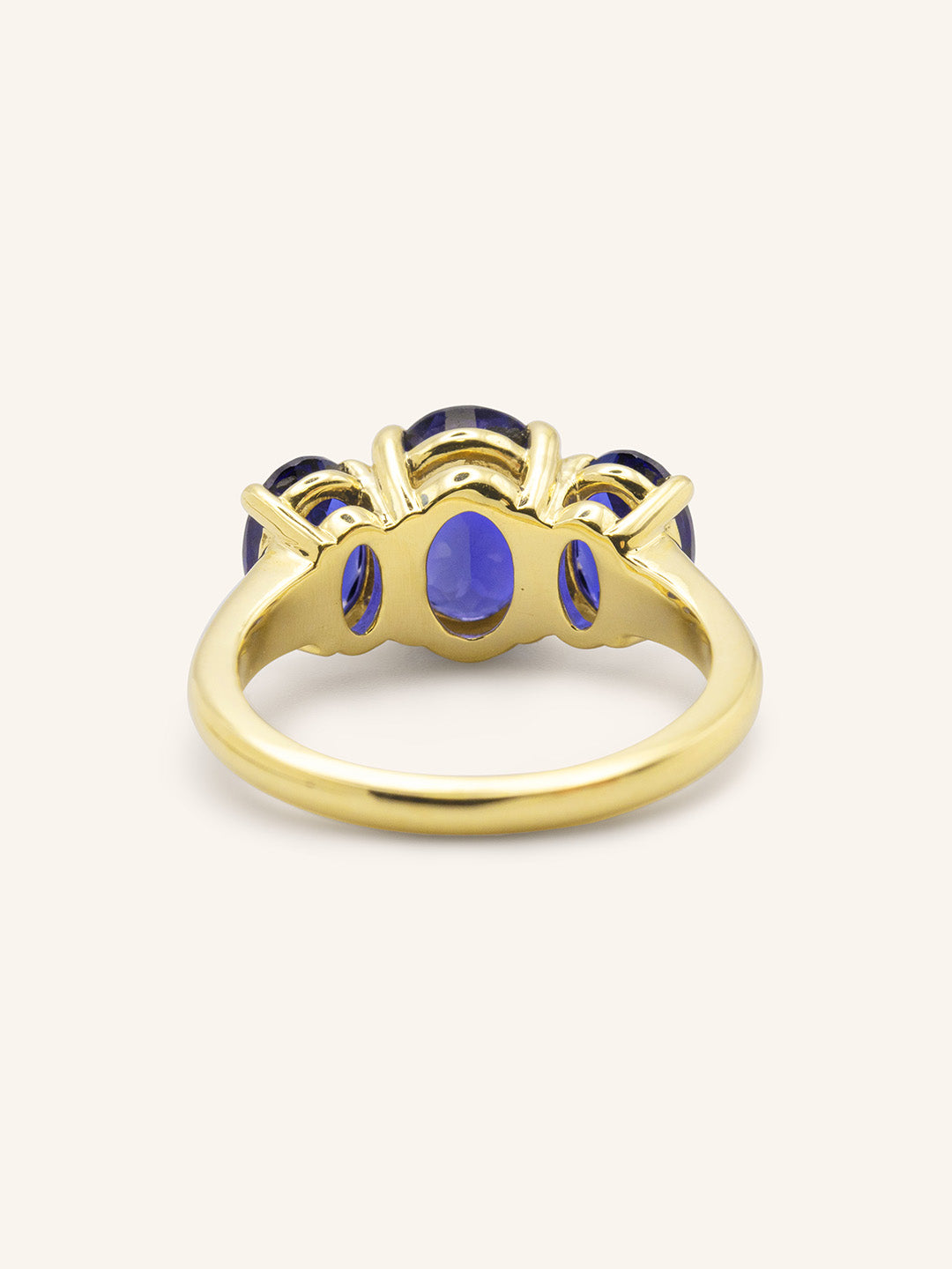 Yellow gold Trielle three stone oval cut blue sapphire ring back view on white background