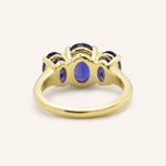 Yellow gold Trielle three stone oval cut blue sapphire ring back view on white background