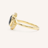 Yellow gold Marlowe oval blue sapphire cluster diamond ring side view on white background