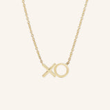 A gold-colored necklace with an X-shaped pendant on a chain.