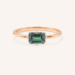 Rose gold solitaire ring with emerald-cut alexandrite gemstone on white background