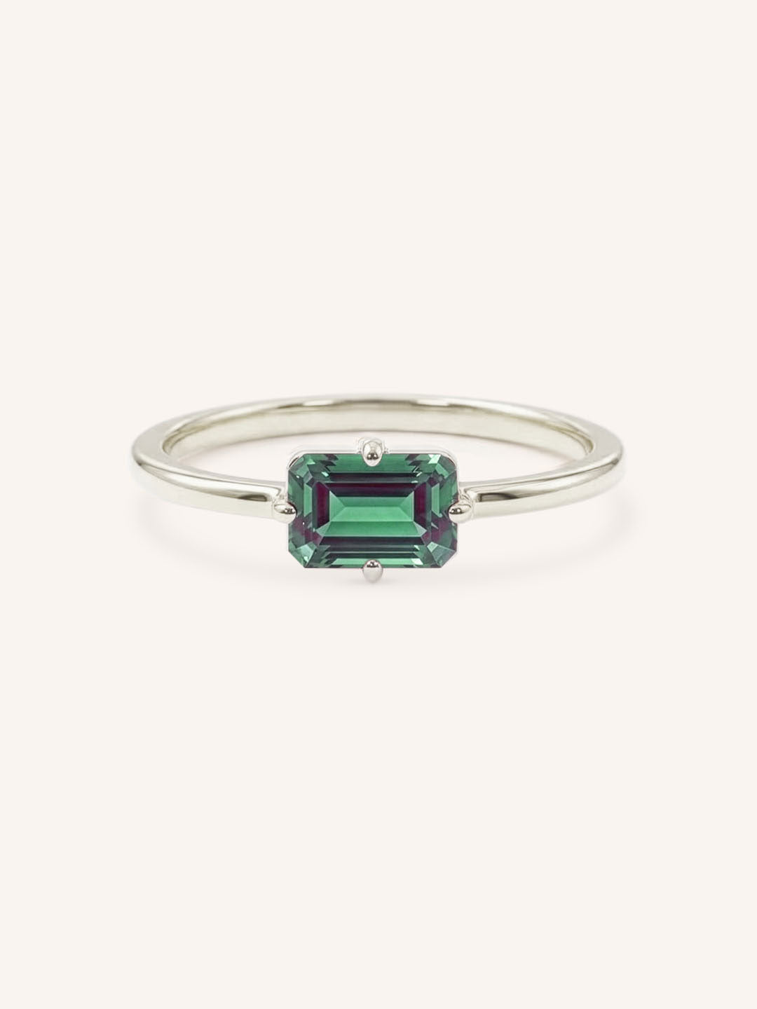 White gold solitaire ring with emerald-cut alexandrite gemstone on white background