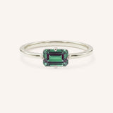 White gold solitaire ring with emerald-cut alexandrite gemstone on white background