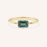 Yellow gold solitaire ring with emerald-cut alexandrite gemstone on white background