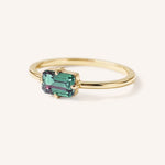 Yellow gold solitaire ring with emerald-cut alexandrite gemstone, side view on white background