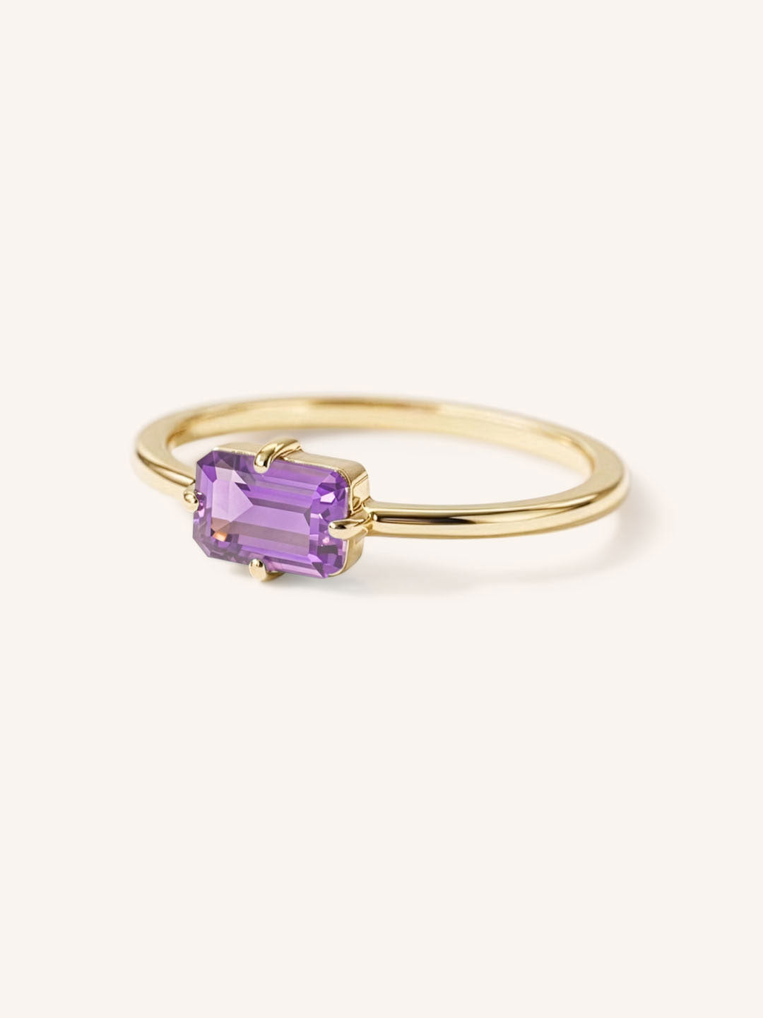 Yellow gold solitaire ring with emerald-cut amethyst gemstone, side view on white background