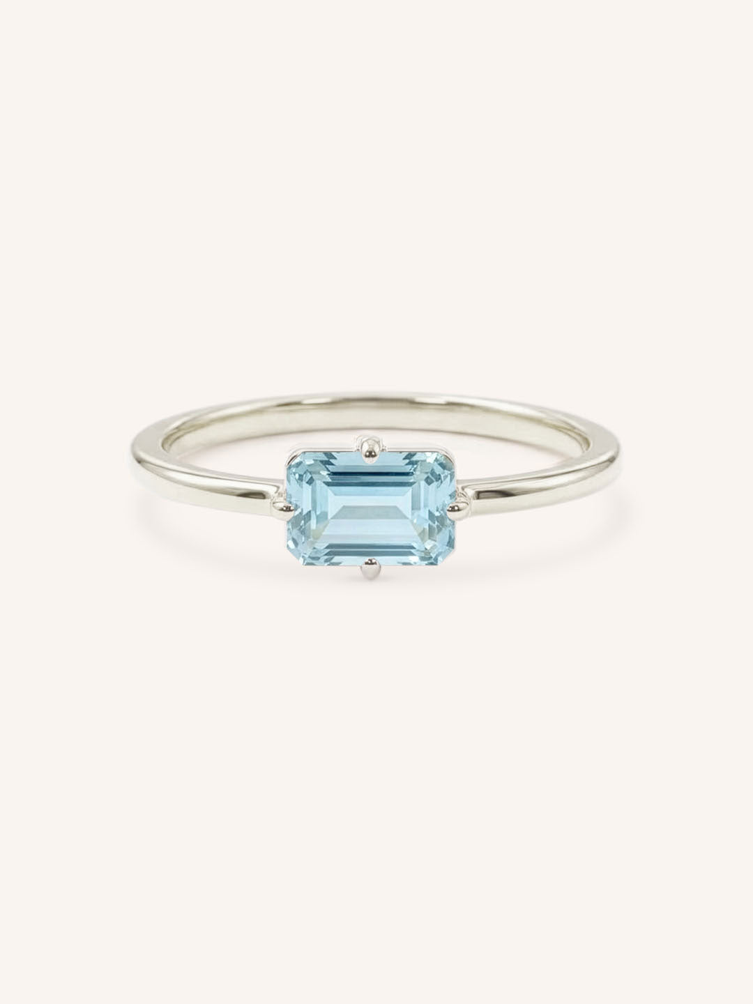 White gold solitaire ring with emerald-cut aquamarine gemstone on white background