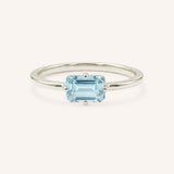 White gold solitaire ring with emerald-cut aquamarine gemstone on white background