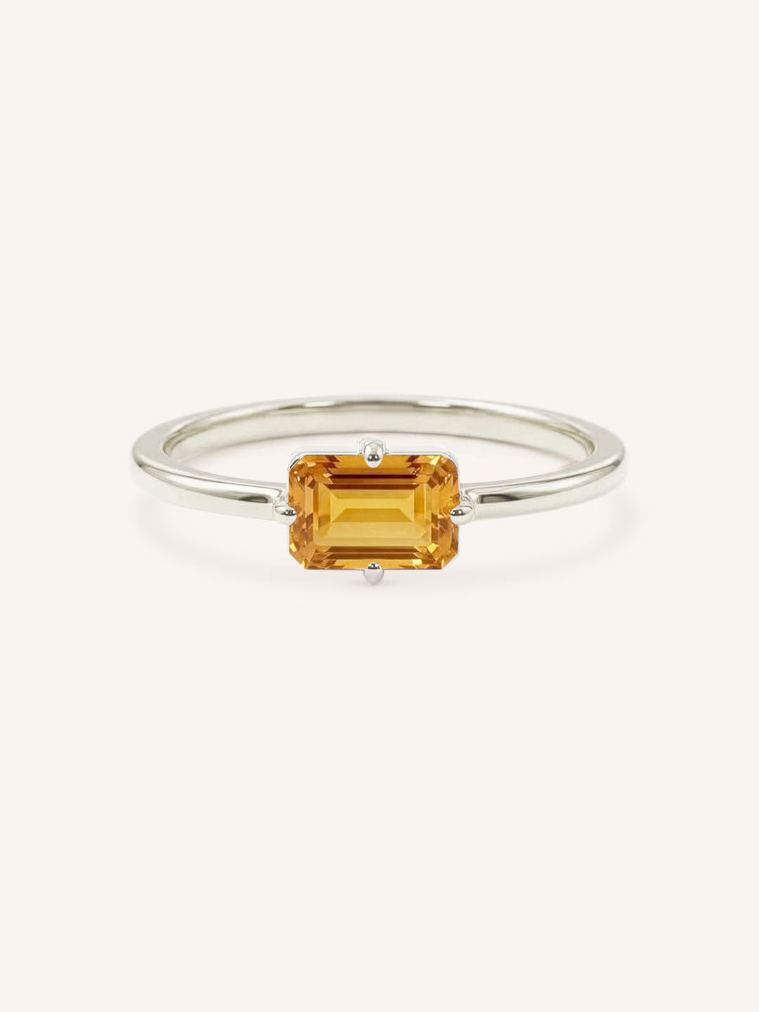 White gold solitaire ring with emerald-cut citrine gemstone on white background