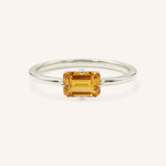White gold solitaire ring with emerald-cut citrine gemstone on white background