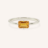 White gold solitaire ring with emerald-cut citrine gemstone on white background