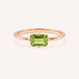 Rose gold solitaire ring with emerald-cut peridot gemstone on white background