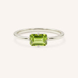 White gold solitaire ring with emerald-cut peridot gemstone on white background