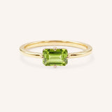 Yellow gold solitaire ring with emerald-cut peridot gemstone on white background