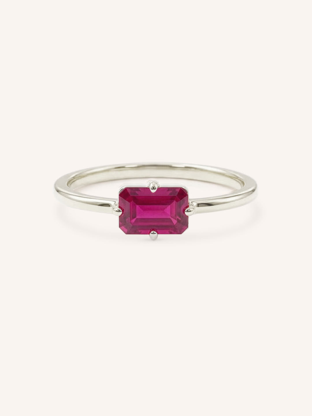 White gold solitaire ring with emerald-cut ruby gemstone on white background
