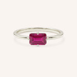 White gold solitaire ring with emerald-cut ruby gemstone on white background
