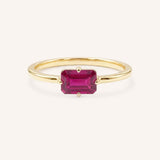 Yellow gold solitaire ring with emerald-cut ruby gemstone on white background