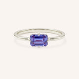 White gold solitaire ring with emerald-cut tanzanite gemstone on white background